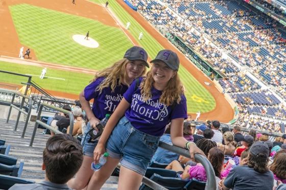  两名2024欧洲杯官方投注唱诗班的女学生穿着相配的紫色t恤，在匹兹堡海盗队的比赛中合影.